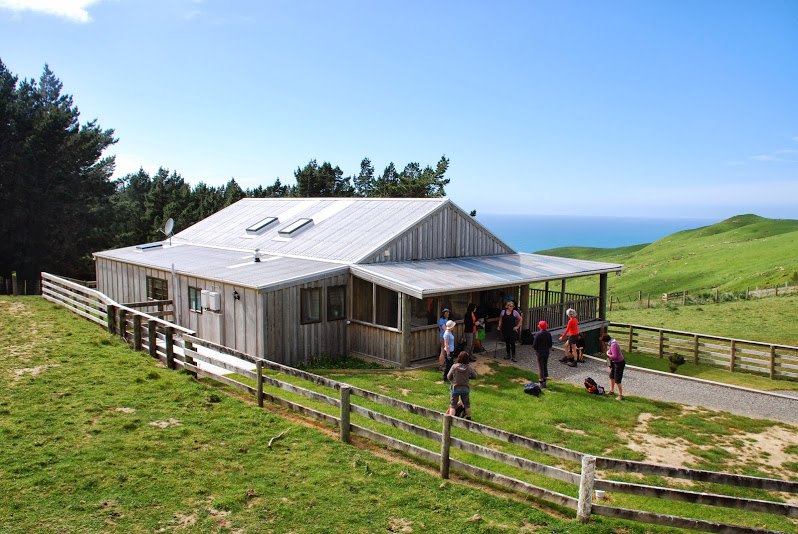 Walkers outside Wai Ngaio Retreat with the sea beyond